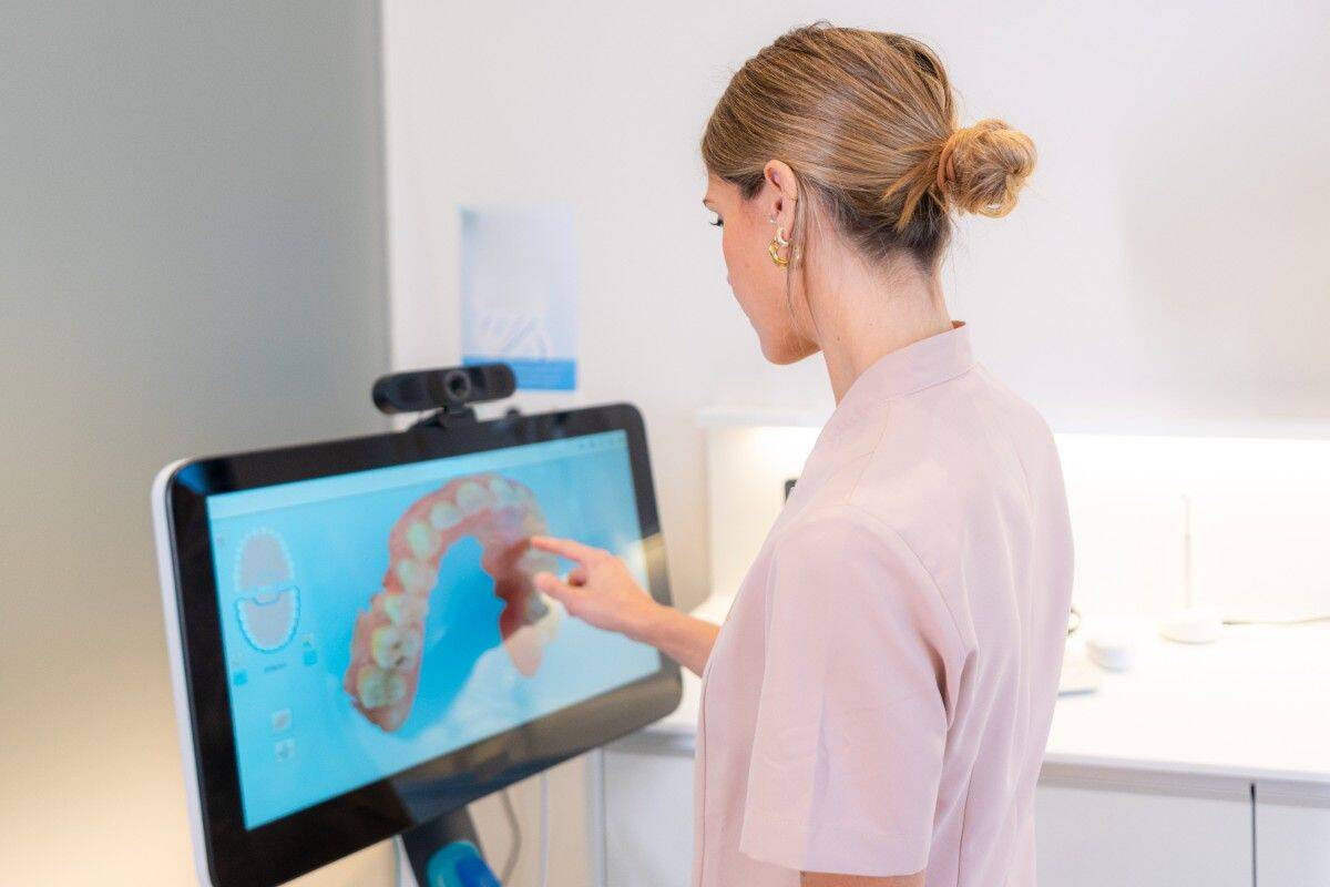Dentist reviewing a 3D digital dental scan on a monitor in a modern dental clinic